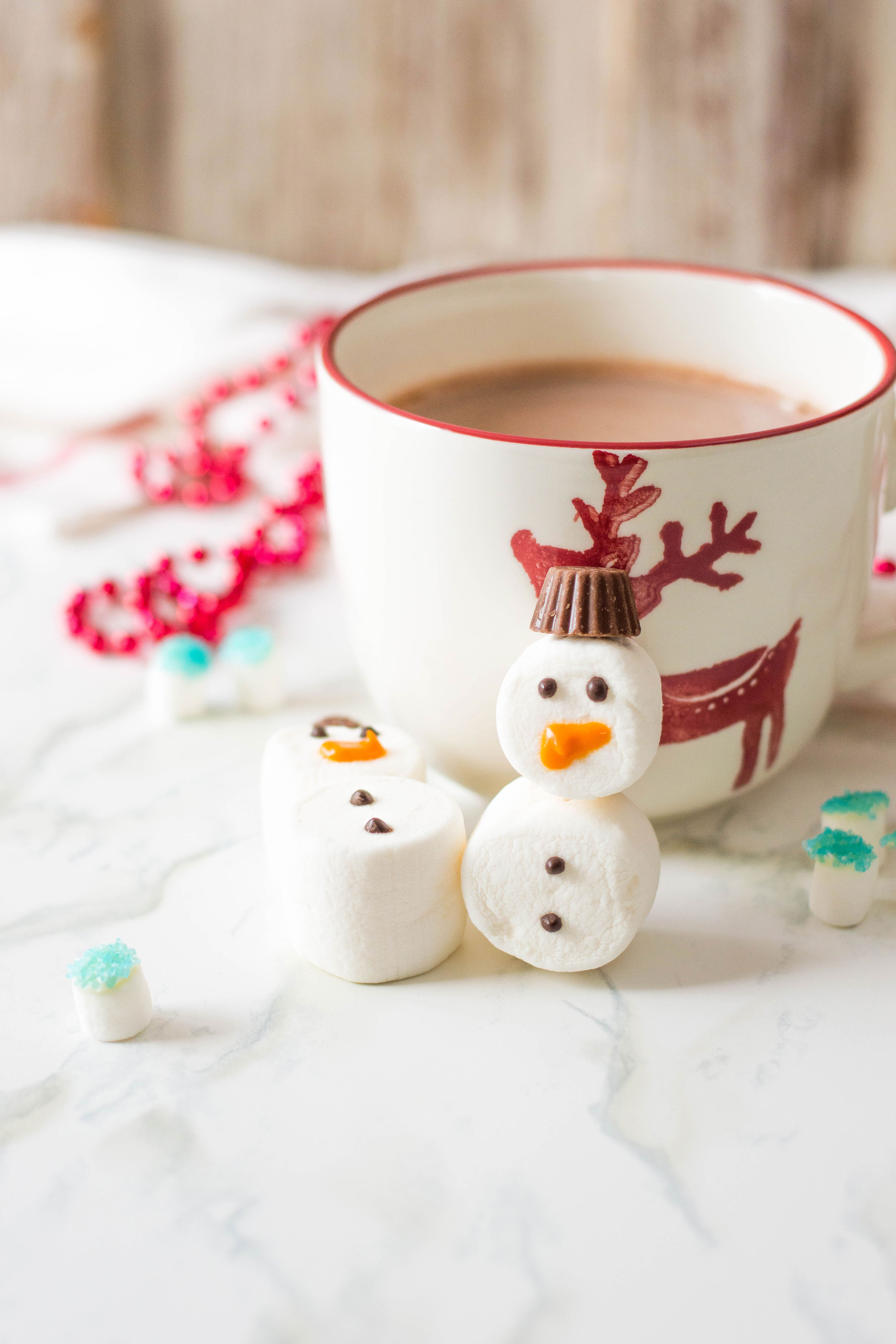 Cute snowman treat standing beside a mug of cocoa.