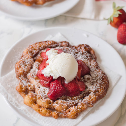 Bring carnival deliciousness right to your home with this delicious Homemade Funnel Cake recipe. Topped with confectioners’ sugar, strawberries and ice cream, the flavor profile to this funnel cake is out of this world!